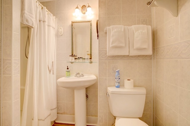 bathroom with sink, curtained shower, toilet, and tile walls