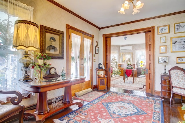 entrance foyer with french doors, a wall mounted AC, crown molding, hardwood / wood-style floors, and a chandelier