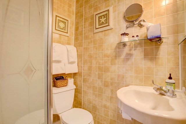 bathroom featuring toilet, sink, and tile walls