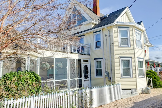 rear view of house with a balcony and a sunroom