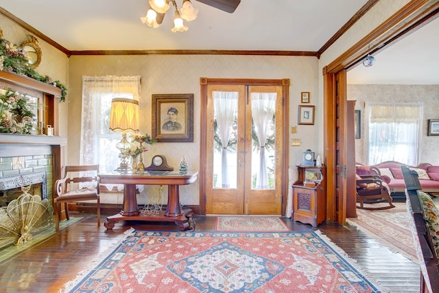 entryway with french doors, ornamental molding, ceiling fan, hardwood / wood-style flooring, and a stone fireplace