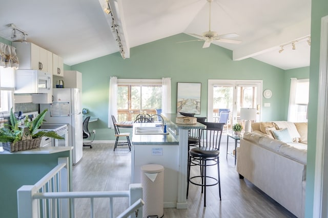 kitchen featuring vaulted ceiling, ceiling fan, sink, hardwood / wood-style floors, and white cabinetry