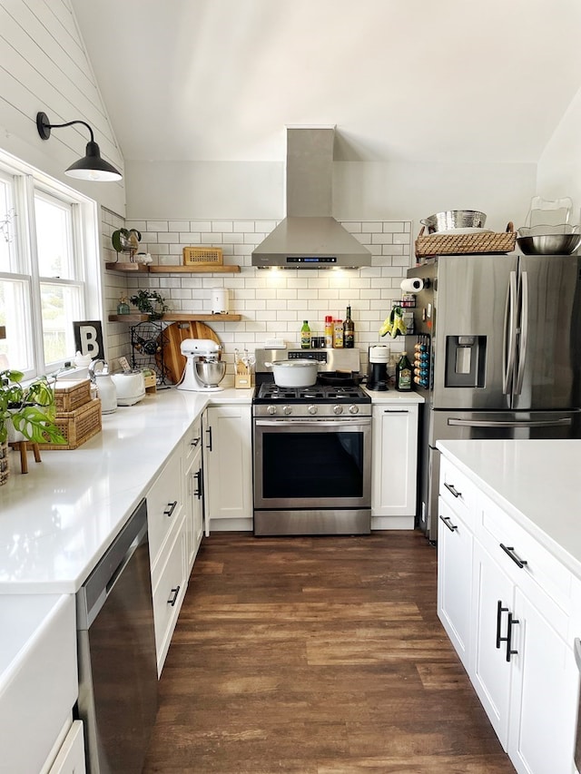 kitchen featuring open shelves, appliances with stainless steel finishes, wall chimney exhaust hood, lofted ceiling, and dark wood-style flooring