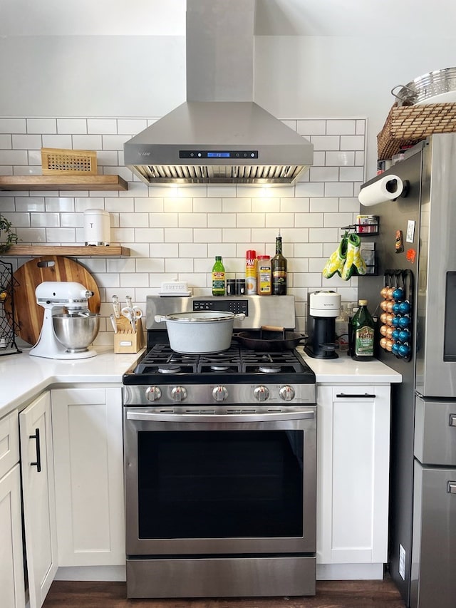 kitchen featuring backsplash, stainless steel appliances, white cabinetry, and wall chimney exhaust hood