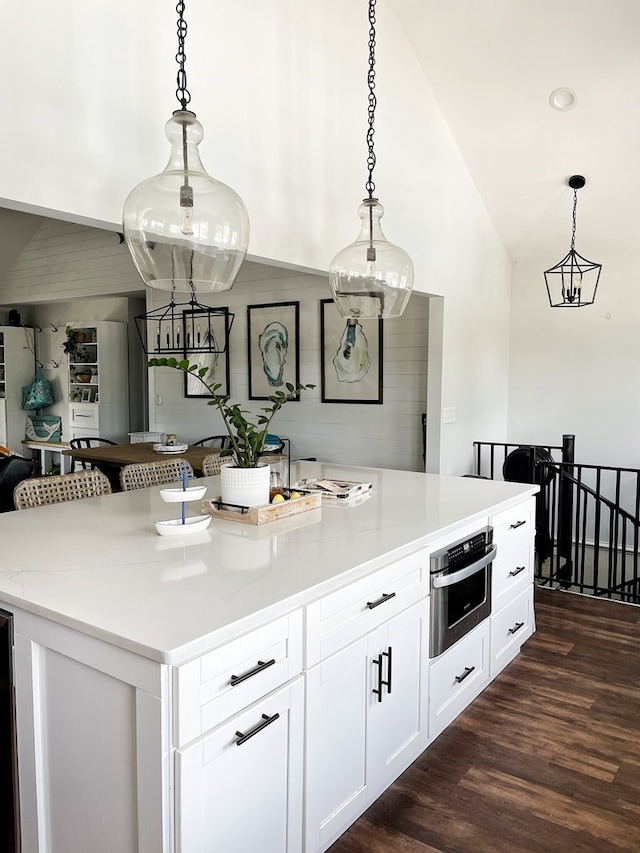 kitchen featuring oven, dark wood-type flooring, a center island, vaulted ceiling, and hanging light fixtures