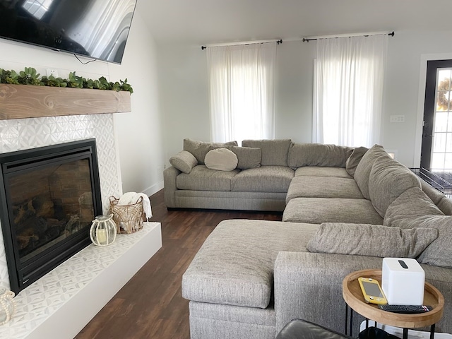 living area with baseboards, dark wood-type flooring, and a tile fireplace