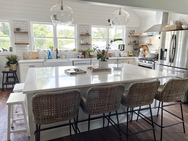 kitchen with a sink, stainless steel appliances, wall chimney range hood, and open shelves