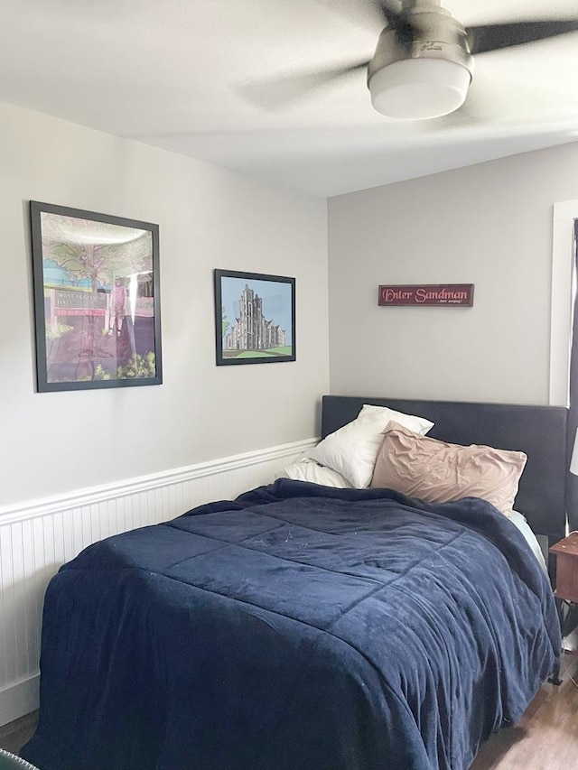 bedroom featuring wainscoting, a ceiling fan, and wood finished floors