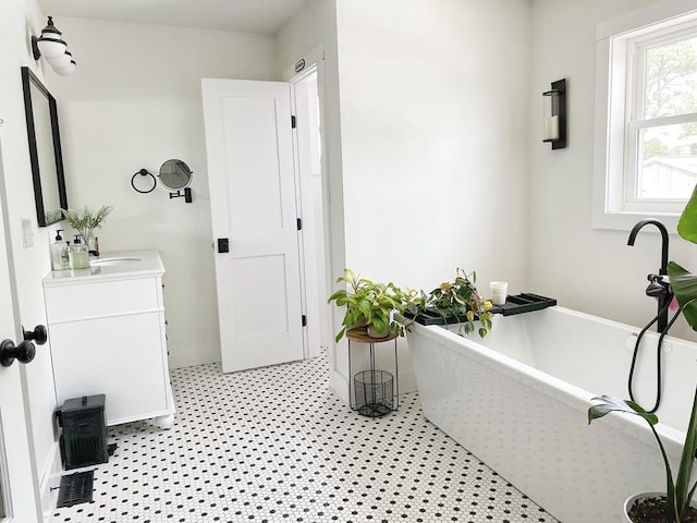 bathroom featuring a soaking tub, vanity, and baseboards