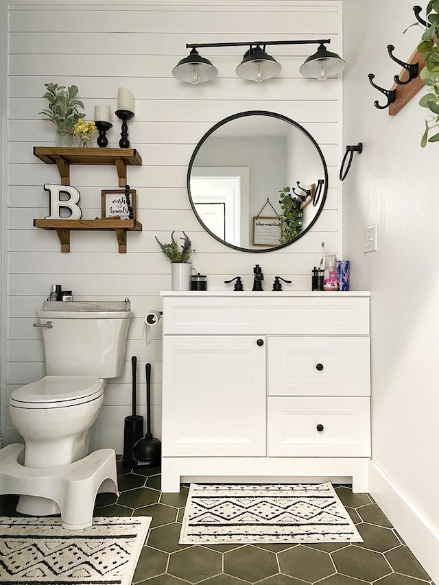 half bathroom with tile patterned floors, baseboards, toilet, and vanity