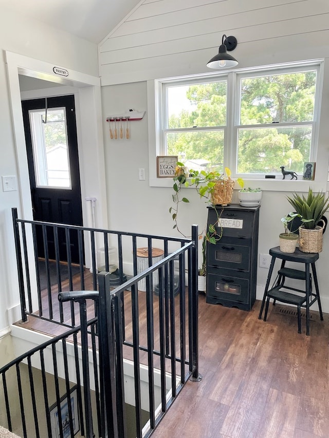 hallway featuring an upstairs landing, plenty of natural light, vaulted ceiling, and wood finished floors