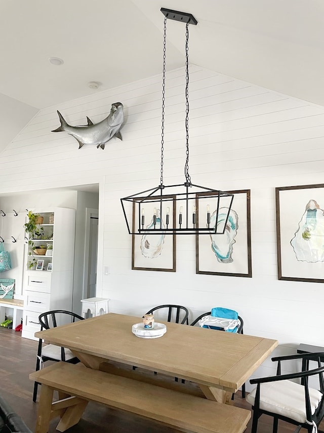 dining space featuring wood walls, a chandelier, vaulted ceiling, and hardwood / wood-style flooring