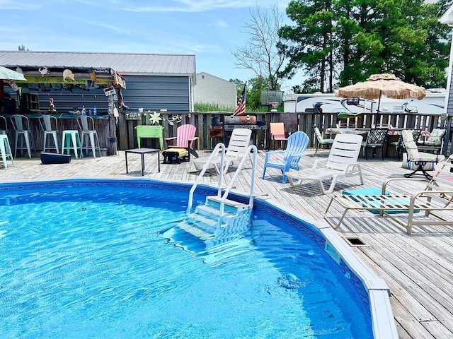 view of pool with exterior bar and a wooden deck