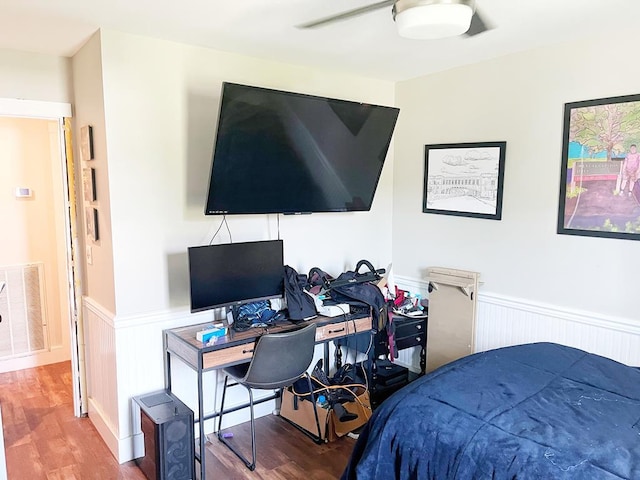 bedroom featuring visible vents, a ceiling fan, wood finished floors, and wainscoting