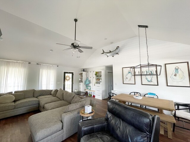 living room featuring ceiling fan with notable chandelier, lofted ceiling, and dark wood-type flooring