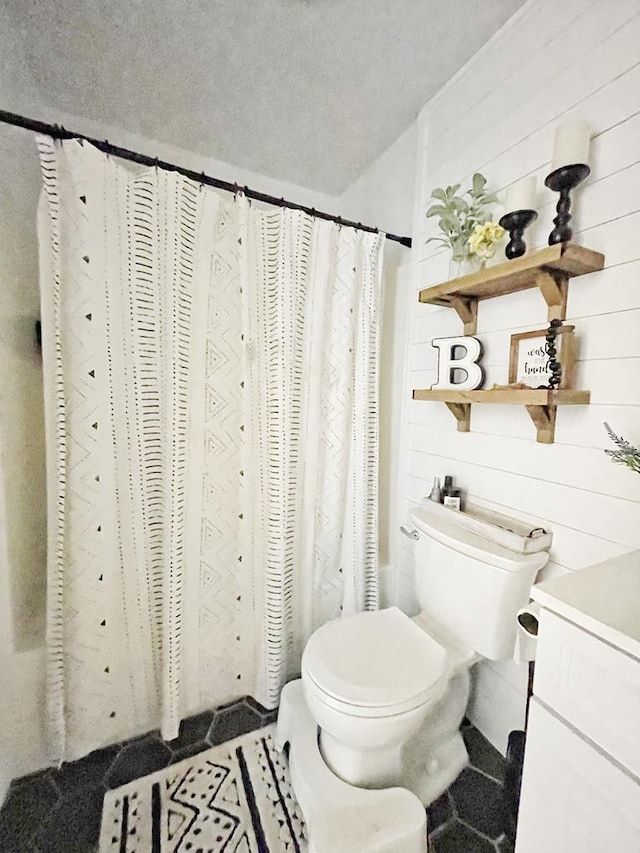 full bathroom with vanity, wood walls, toilet, and shower / tub combo