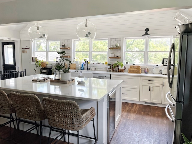 kitchen featuring wine cooler, dark wood finished floors, light countertops, a kitchen breakfast bar, and stainless steel appliances