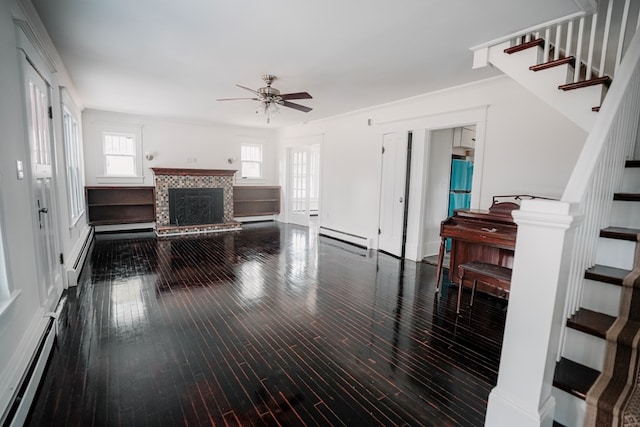 living room with ceiling fan, wood-type flooring, a fireplace, and a baseboard heating unit