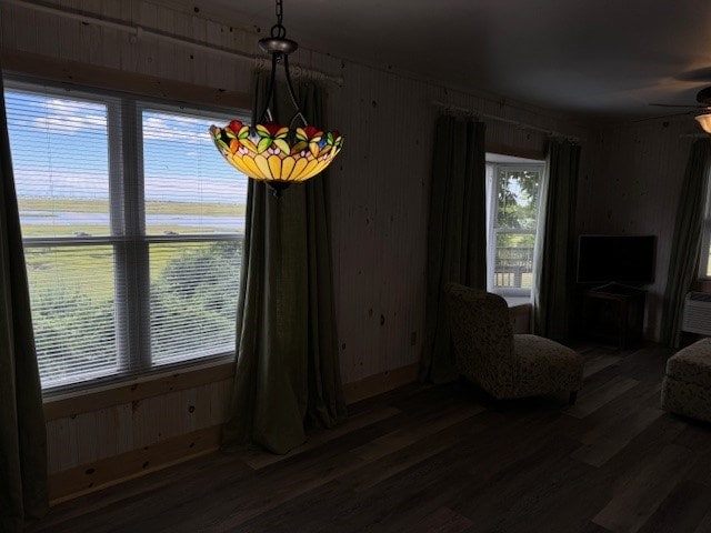 dining room with ceiling fan, dark wood-type flooring, and wood walls