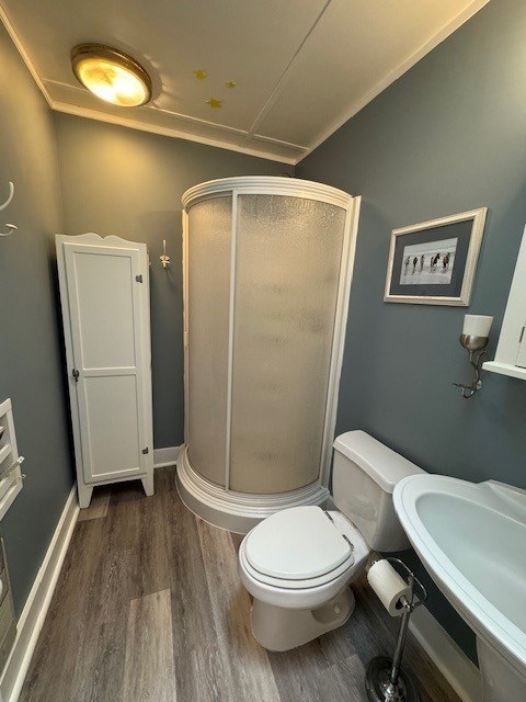 bathroom featuring toilet, a shower with door, hardwood / wood-style floors, and sink