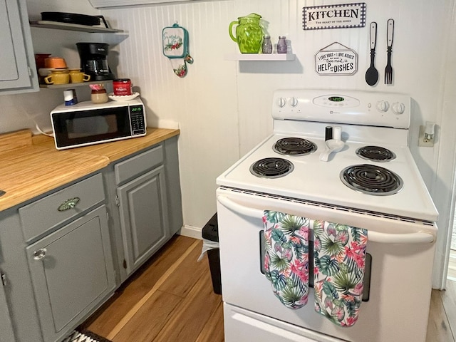 kitchen with wood-type flooring, butcher block countertops, gray cabinets, and electric stove