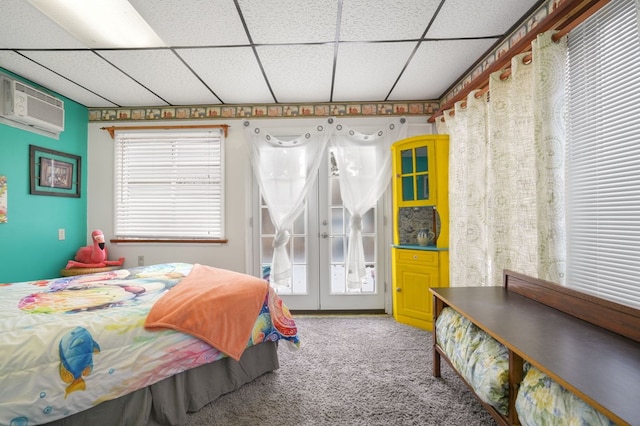 bedroom with a paneled ceiling, carpet flooring, a wall mounted air conditioner, and multiple windows