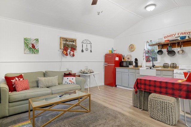 living room with a wall mounted AC, sink, lofted ceiling, and light hardwood / wood-style flooring