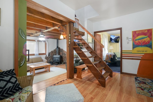 bedroom featuring beamed ceiling, wood-type flooring, and a wood stove