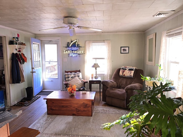 living room with wood-type flooring, ornamental molding, and ceiling fan