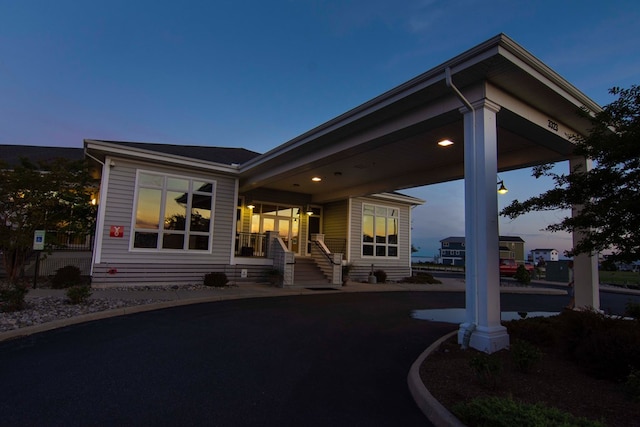 back house at dusk featuring covered porch