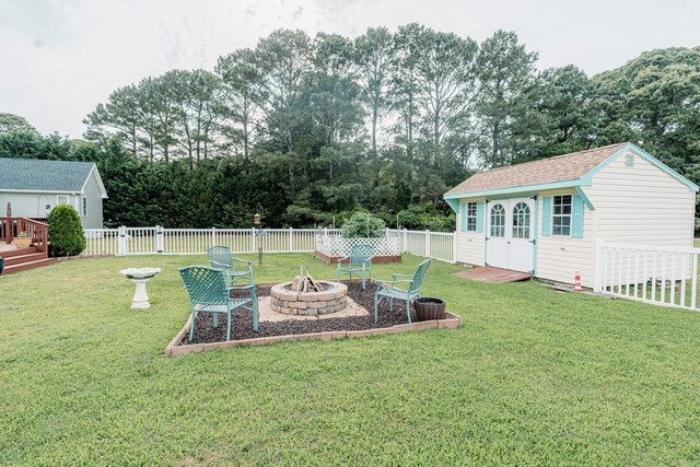 37275 Longboat Ct, Greenbackville, VA 23356 - fenced backyard featuring a fire pit, an outdoor structure, and view of wooded area