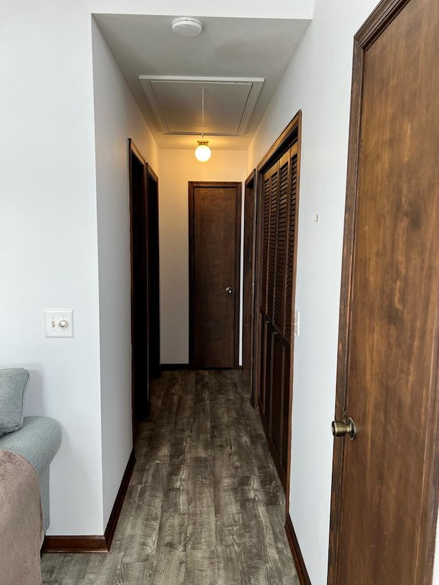 hall with dark wood-style floors, attic access, and baseboards