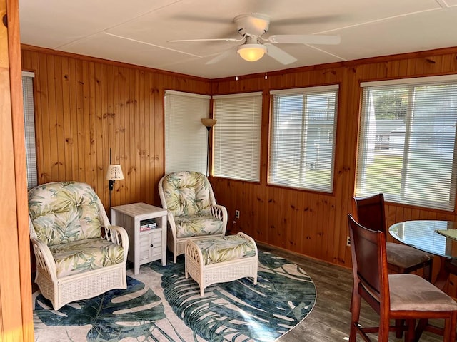 sitting room featuring ceiling fan, wood walls, and wood finished floors