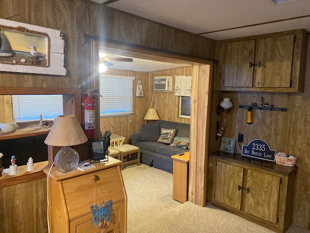 carpeted living room with an AC wall unit, wood walls, and ceiling fan