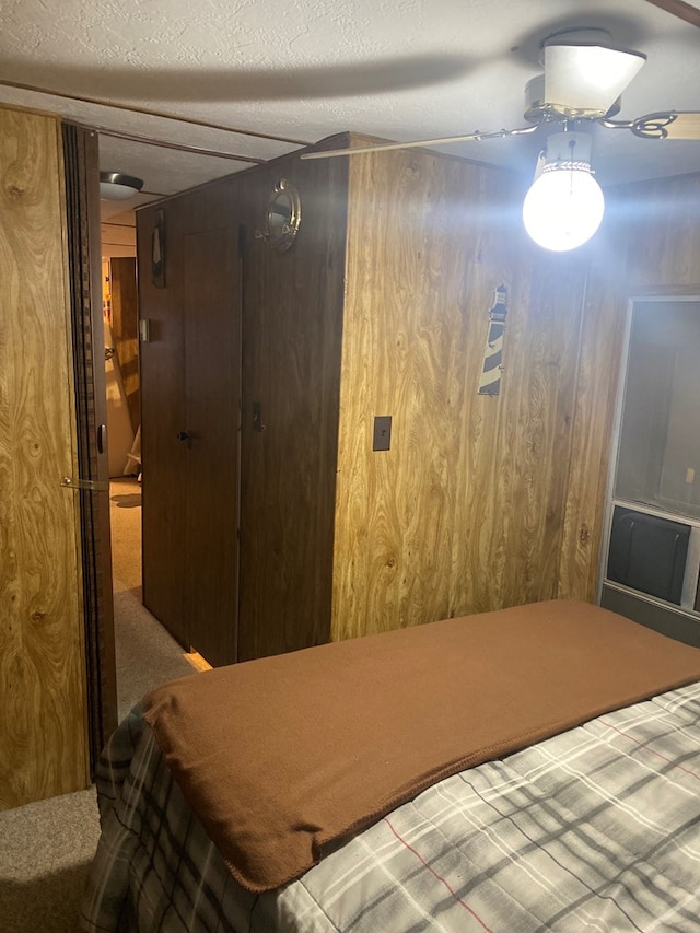 carpeted bedroom featuring a textured ceiling, ceiling fan, and wooden walls