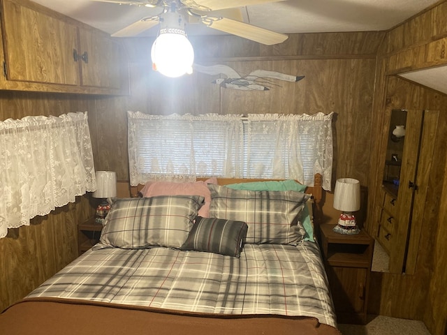 bedroom with ceiling fan and wood walls