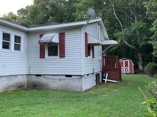 view of side of home featuring a yard and a storage unit