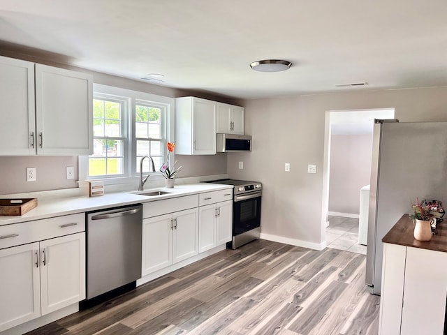 3469 Willis Wharf Rd, Exmore, VA 23350 - kitchen with appliances with stainless steel finishes, white cabinetry, and light wood-style floors