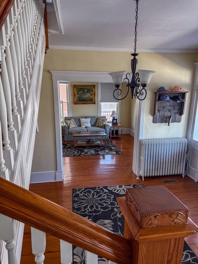 interior space with ornamental molding, radiator, baseboards, and wood finished floors