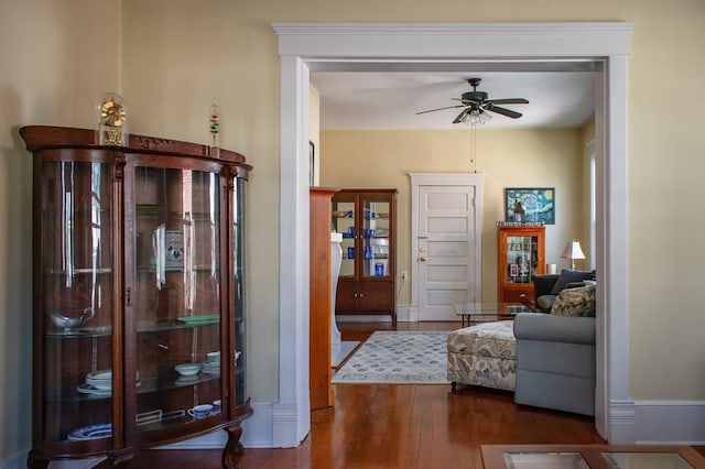 interior space featuring a ceiling fan, baseboards, and hardwood / wood-style flooring