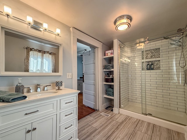 bathroom featuring a stall shower, wood finish floors, and vanity