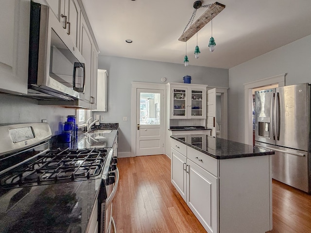 kitchen with light wood-type flooring, a kitchen island, white cabinetry, and stainless steel appliances