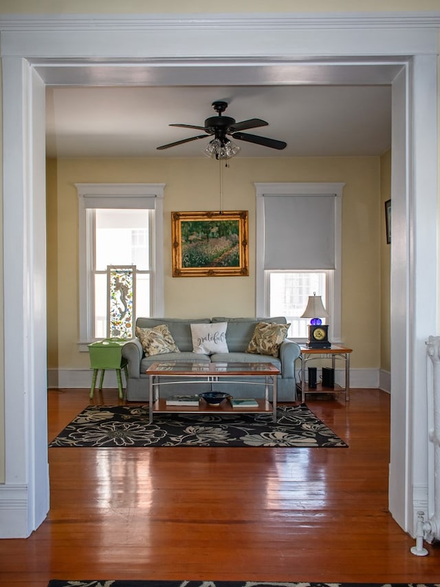 living area with ceiling fan, baseboards, and wood finished floors