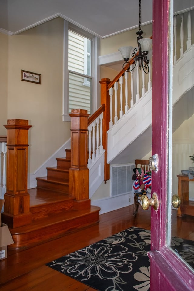 stairway with visible vents, a chandelier, and wood finished floors