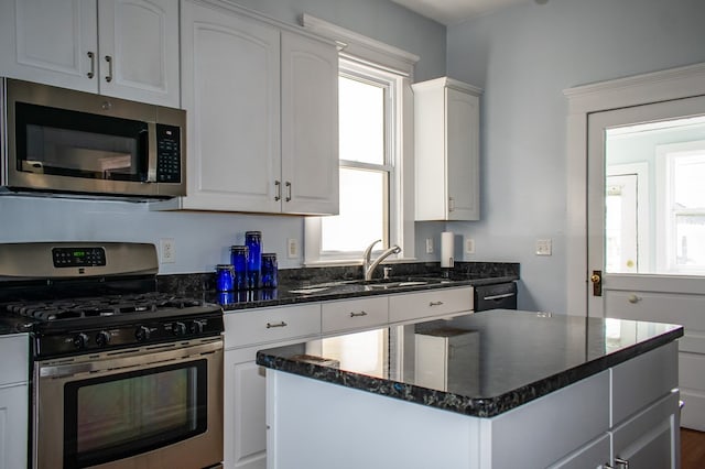 kitchen featuring a healthy amount of sunlight, stainless steel appliances, a sink, and a center island