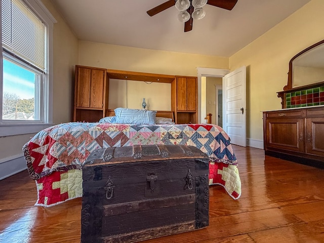 bedroom with a ceiling fan, baseboards, and wood finished floors