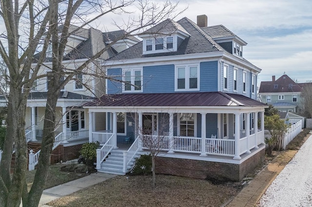 traditional style home with covered porch, metal roof, a chimney, and fence