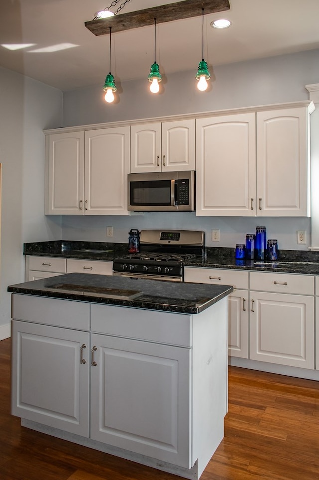 kitchen featuring appliances with stainless steel finishes, white cabinets, wood finished floors, and pendant lighting