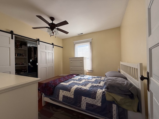 bedroom with a barn door, visible vents, and a ceiling fan