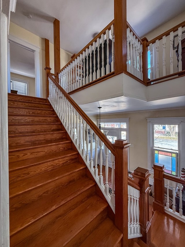 stairs with a towering ceiling and wood finished floors